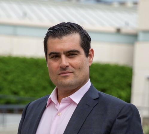 Brian Keating, smiling in a dark blue suit jacket and pink shirt