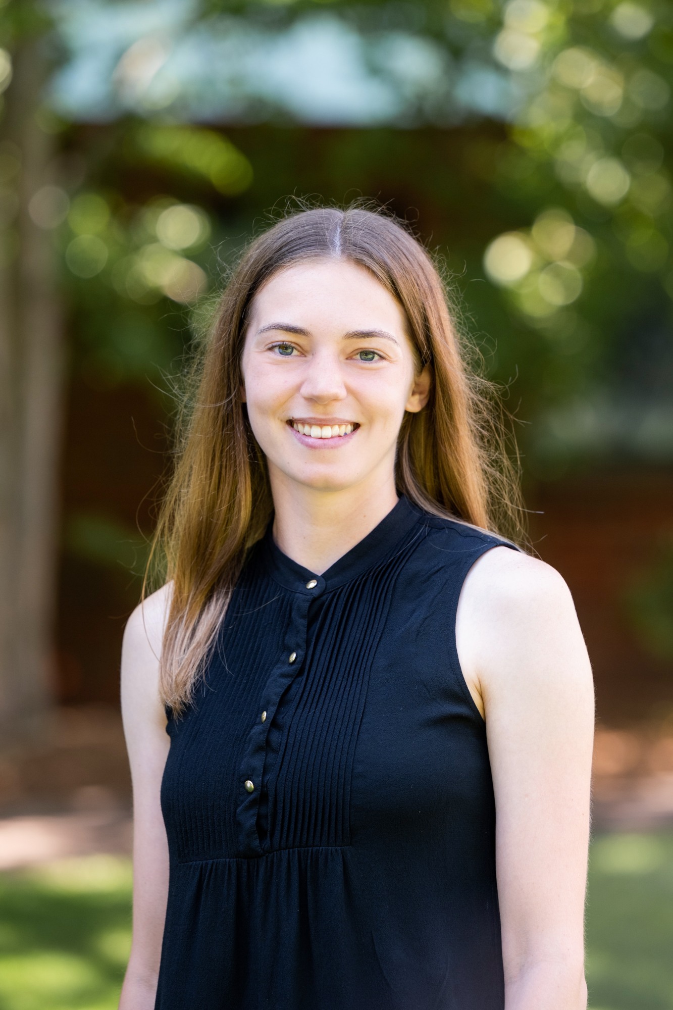 Kristin Kimble in a black shirt standing in front of green trees.