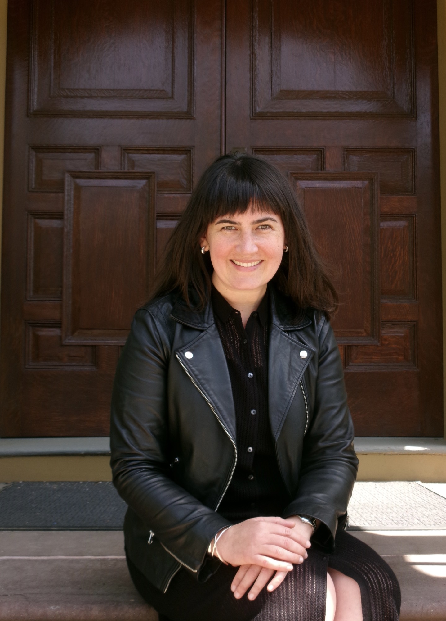 image of Kate Elizabeth Creasey sitting on steps in a dark jacket and skirt