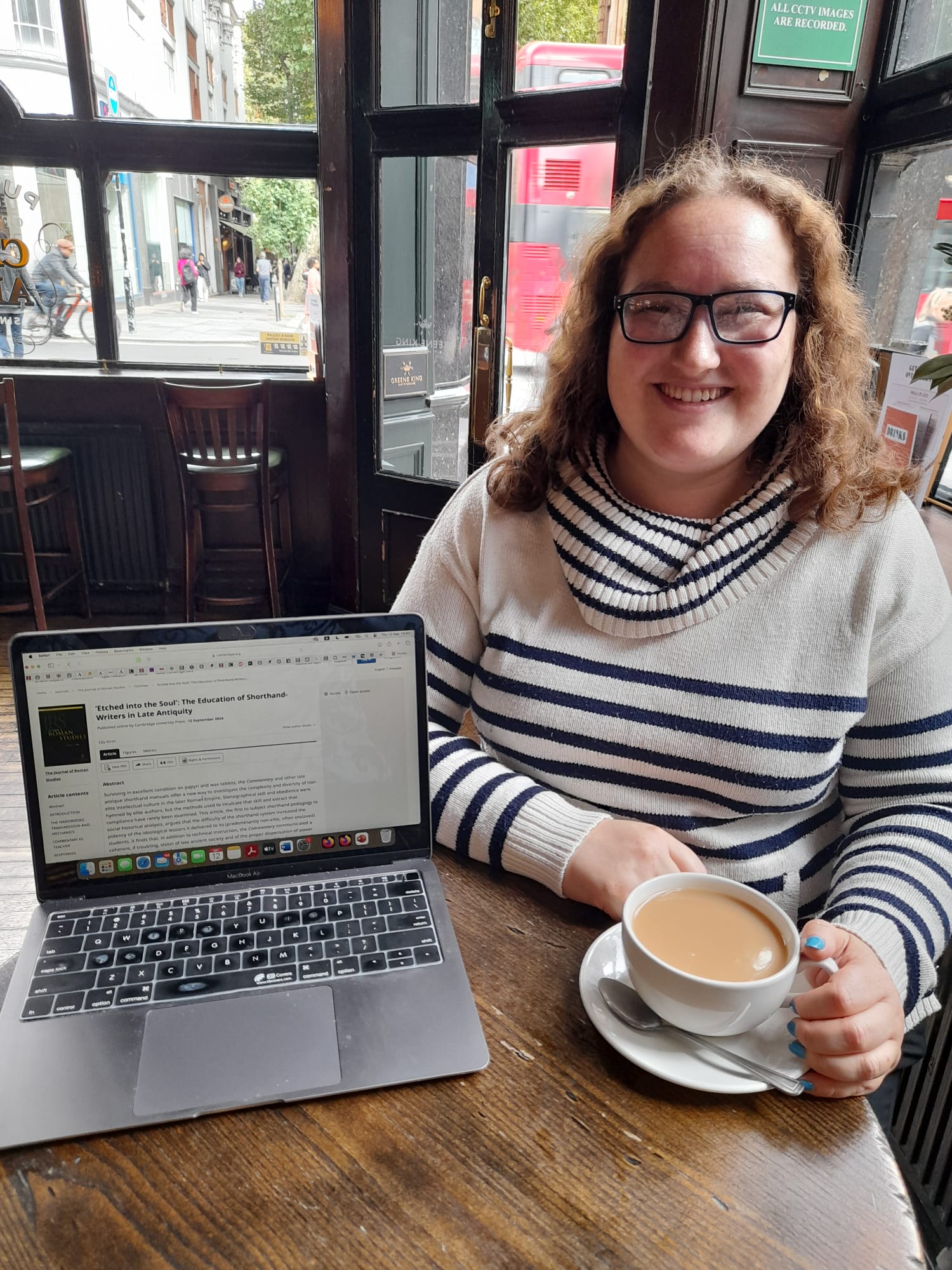 Ella Kirsh at a table with a laptop and a cup of coffee