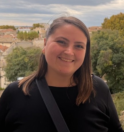 Brianna Hoegler, a fourth-year Ph.D. candidate, smiling and looking toward the camera while standing outdoors with a natural background.