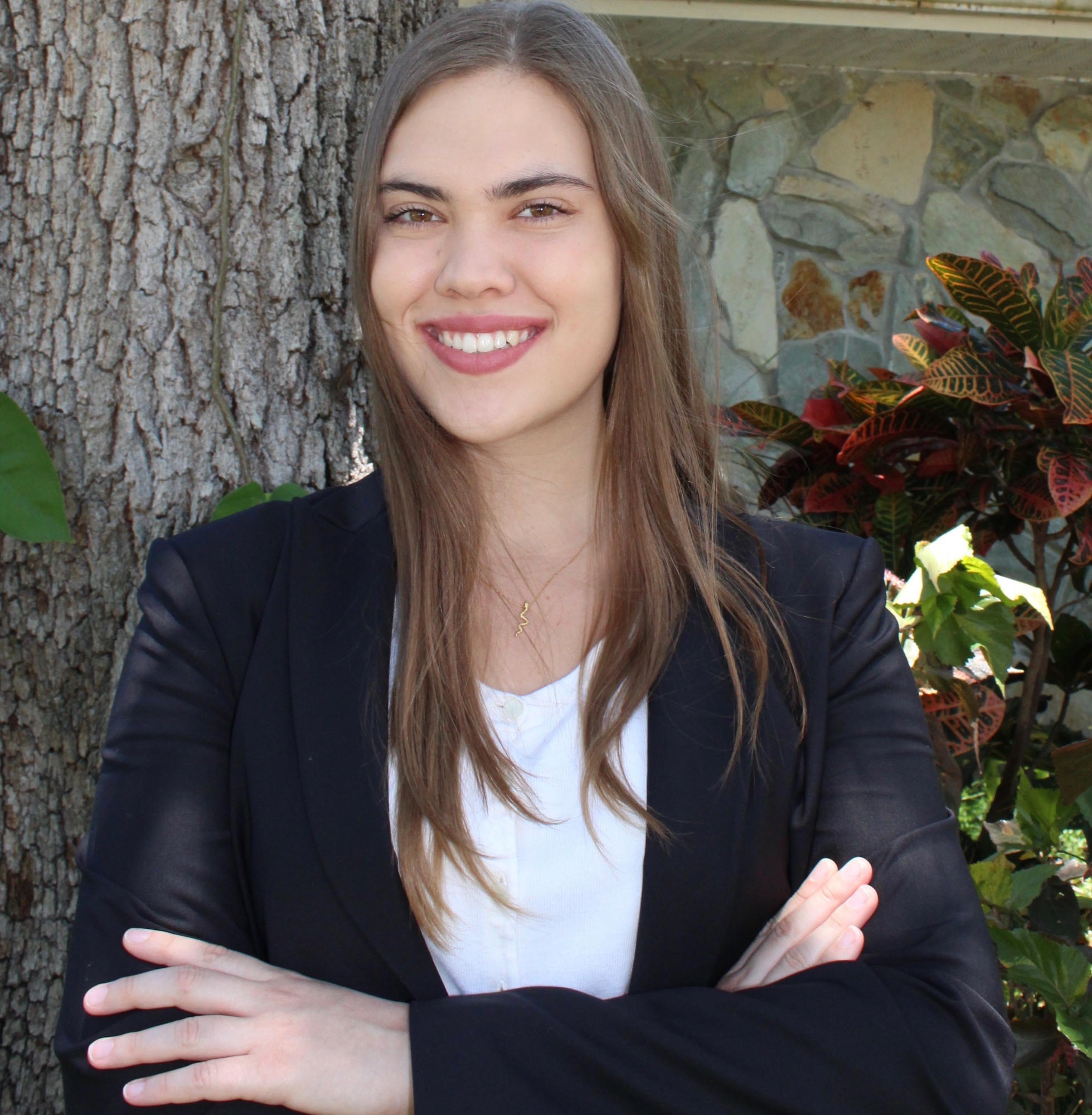 headshot of Isabella Schultz in a black jacket over a white shirt in front of a tree