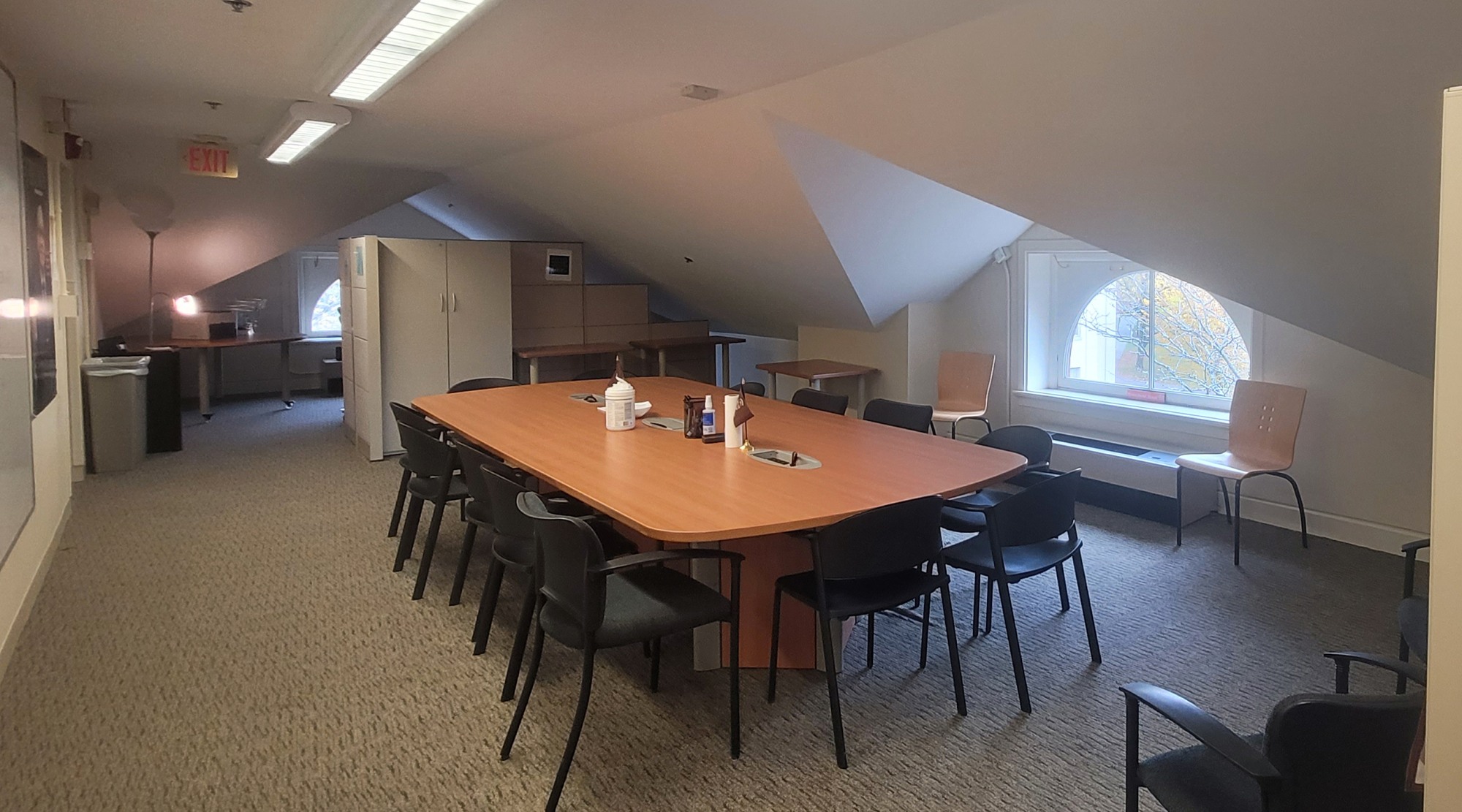 long meeting table in the center of the room with a window on the far side in the middle.