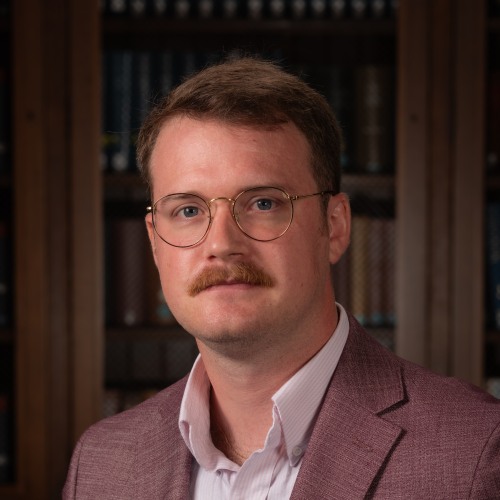 Michael Anzalone in brown suit jacket and light shirt with a dark background