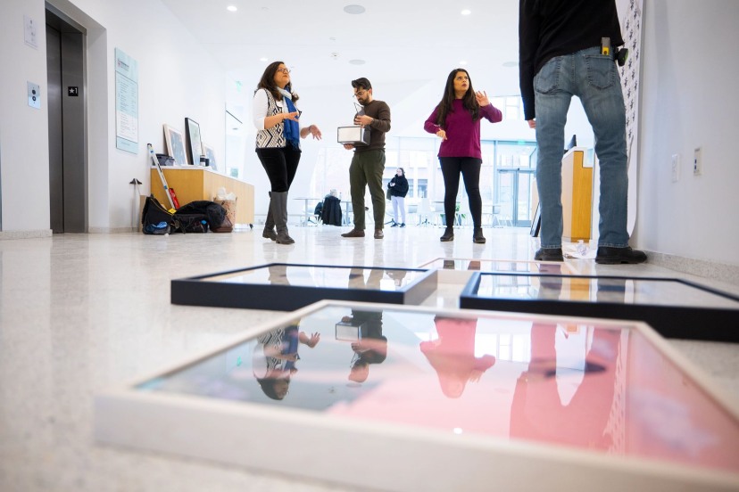  Brown doctoral student working with Brown staff to hang works of art